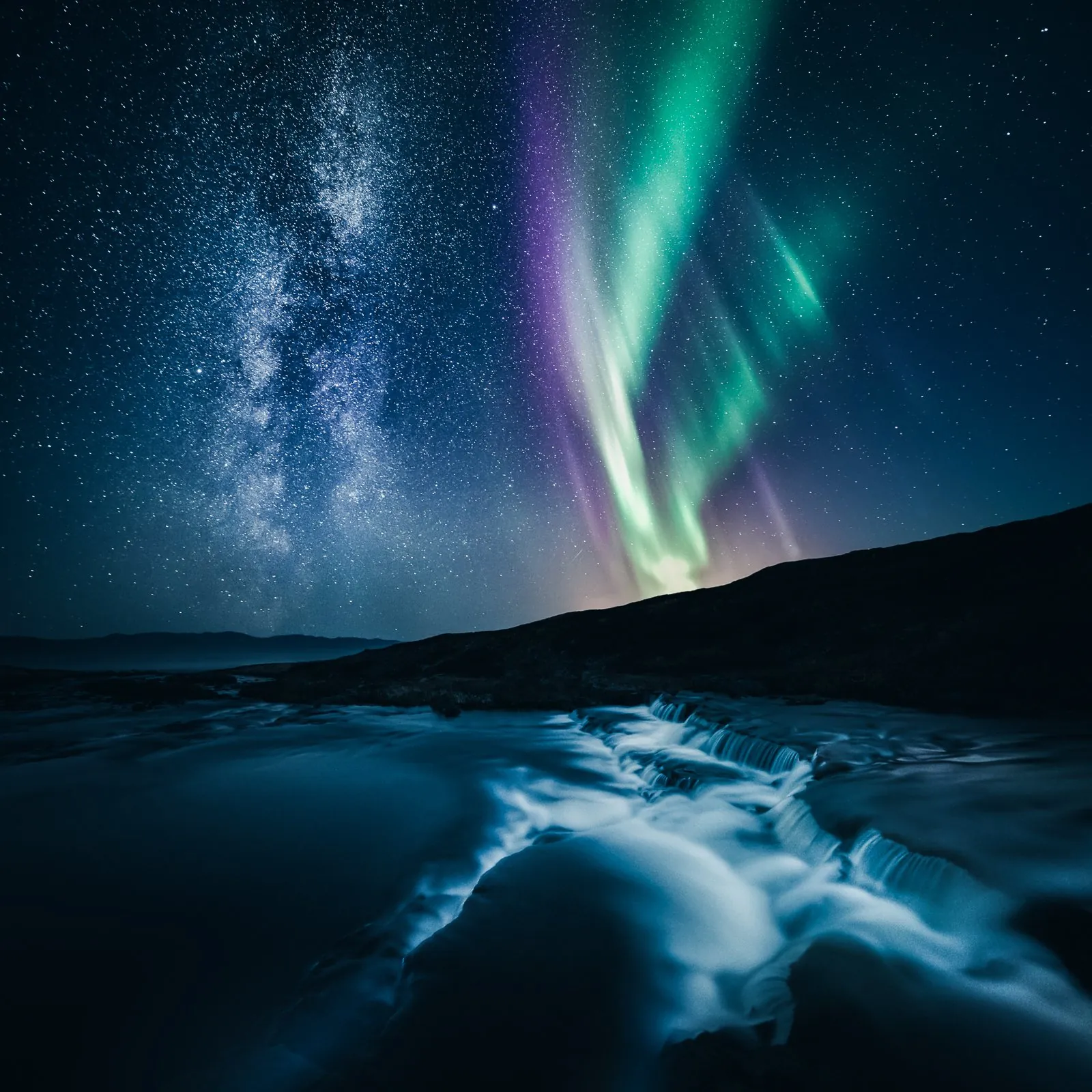 Milky Way and aurora filling the northern night sky above still water